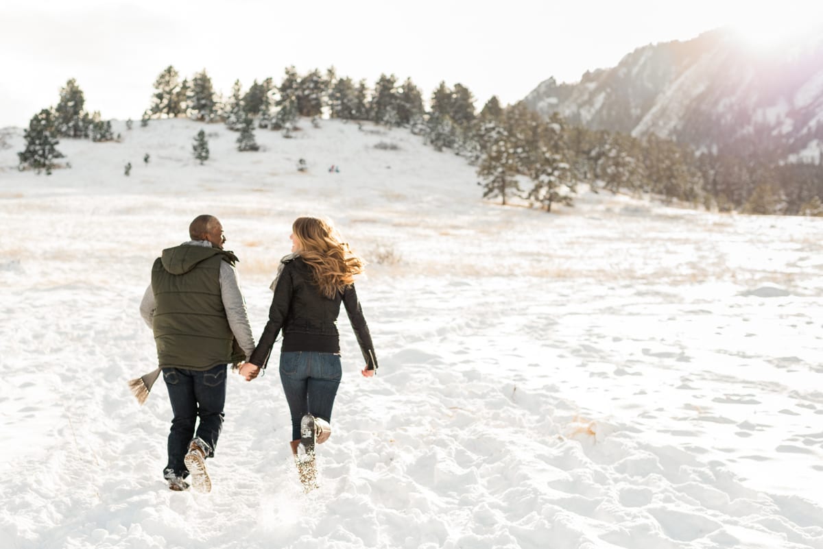 Engaged couple embracing in winter proposal photoshoot with golden hour sunlight creating warm atmospheric effect