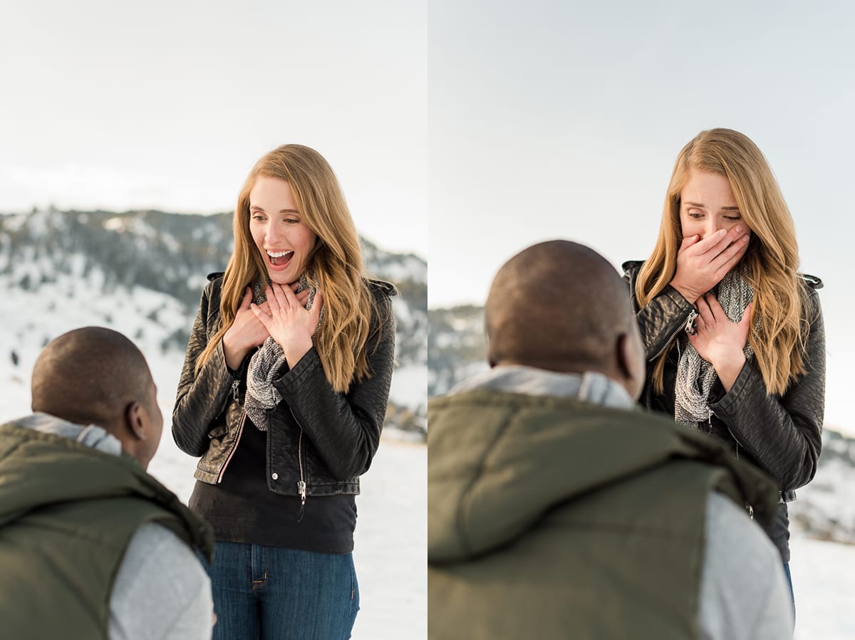 Engaged couple standing together with snow-covered Flatirons mountain range visible in winter landscape background