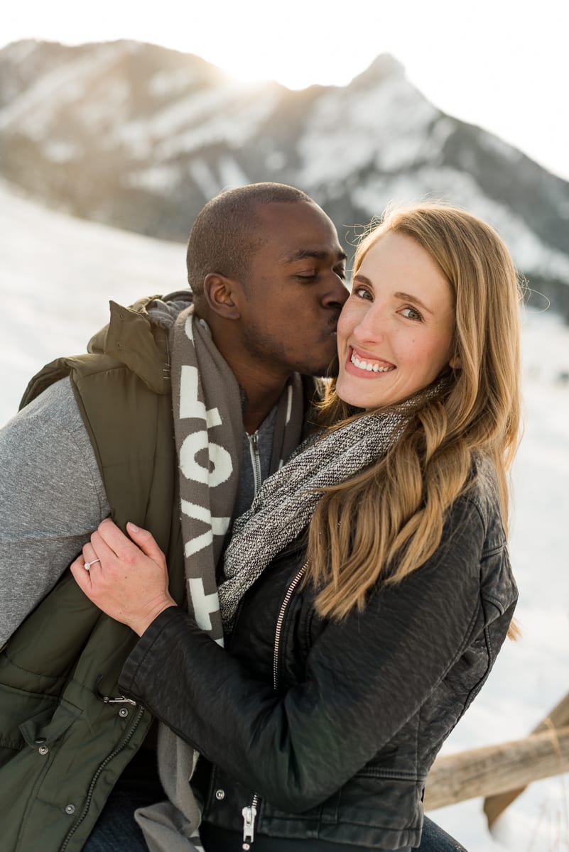 Vertical portrait engagement photo of woman in winter setting with genuine emotional expression and mountain backdrop