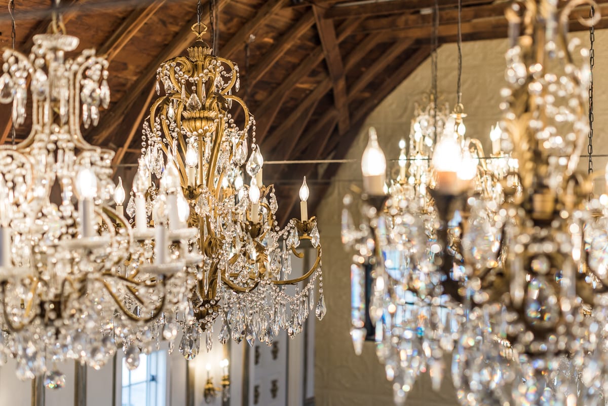Intimate view of handcrafted chandeliers and original barn beams in the Chandelier Barn showing rustic and glamorous design elements