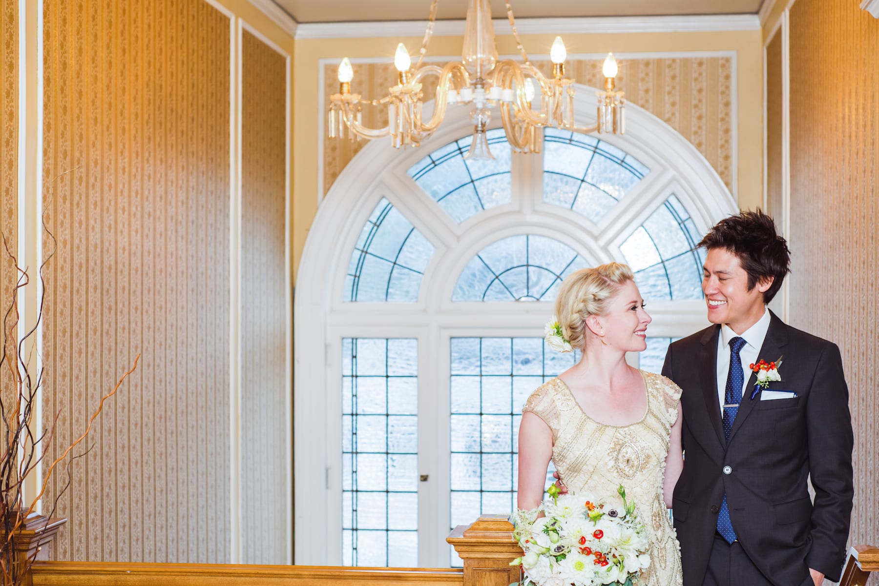 Happy couple sharing a laugh in front of a large window during their intimate elopement portraits