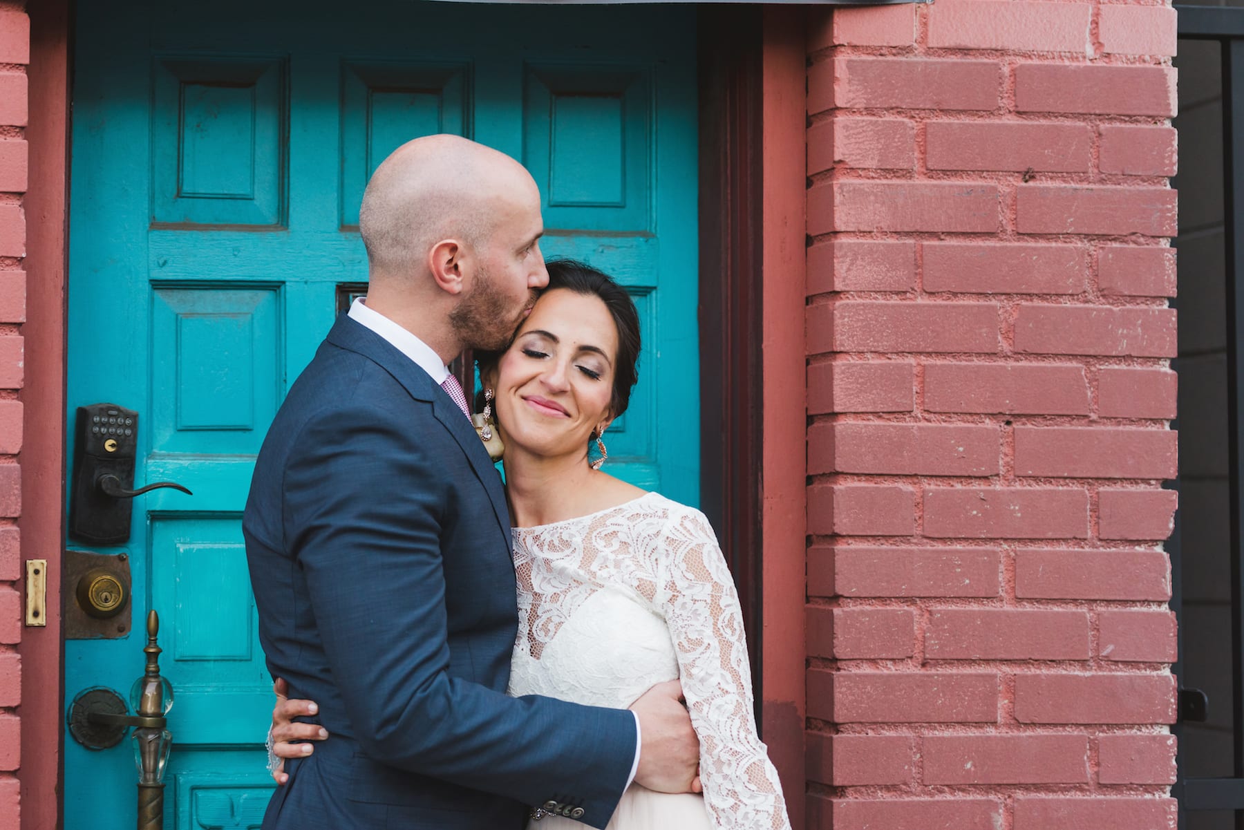 Newlywed couple embracing in front of a vibrant blue doorway during their Colorado elopement