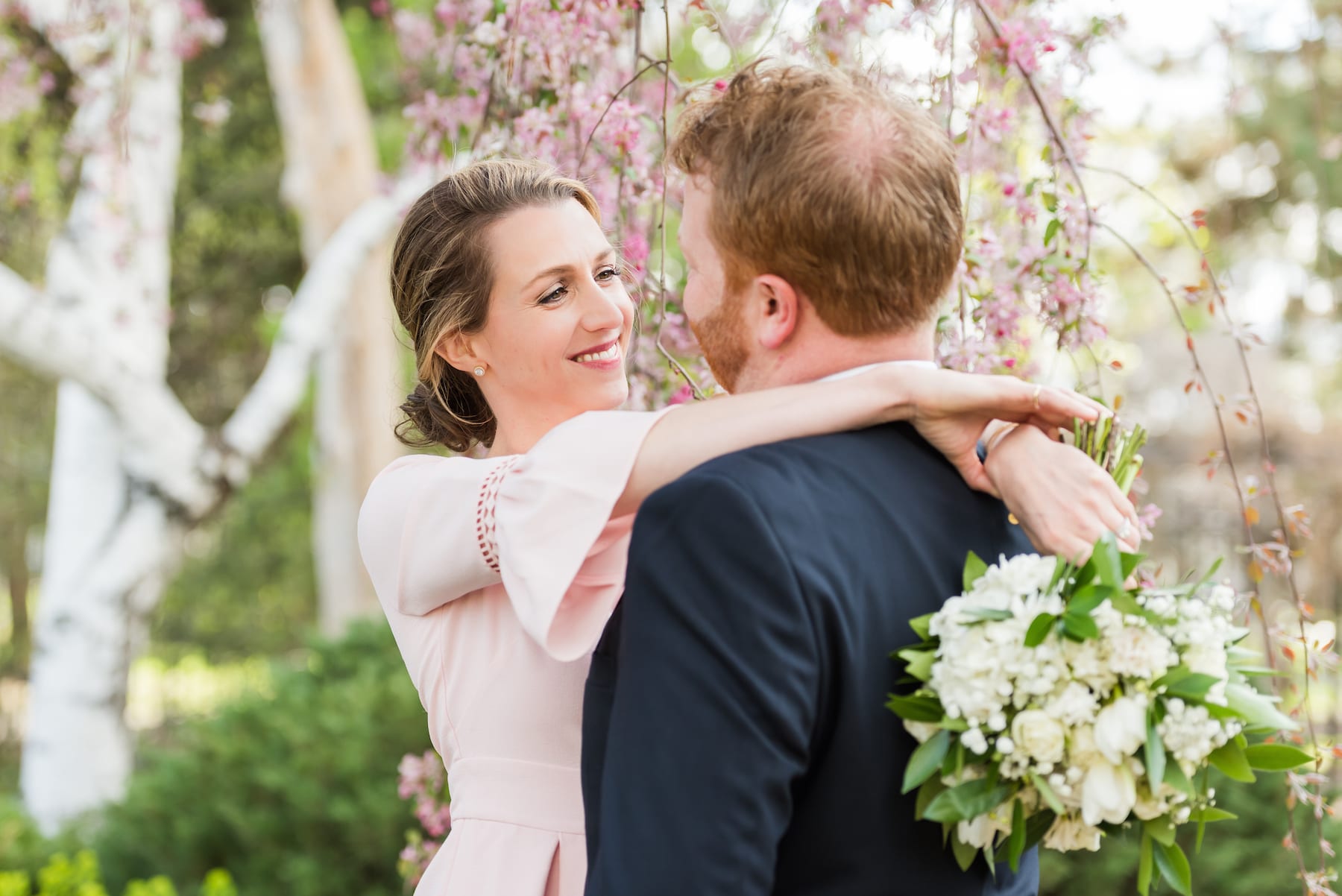 Couple smiling at one another surrounded by blooming flowers at a garden elopement venue