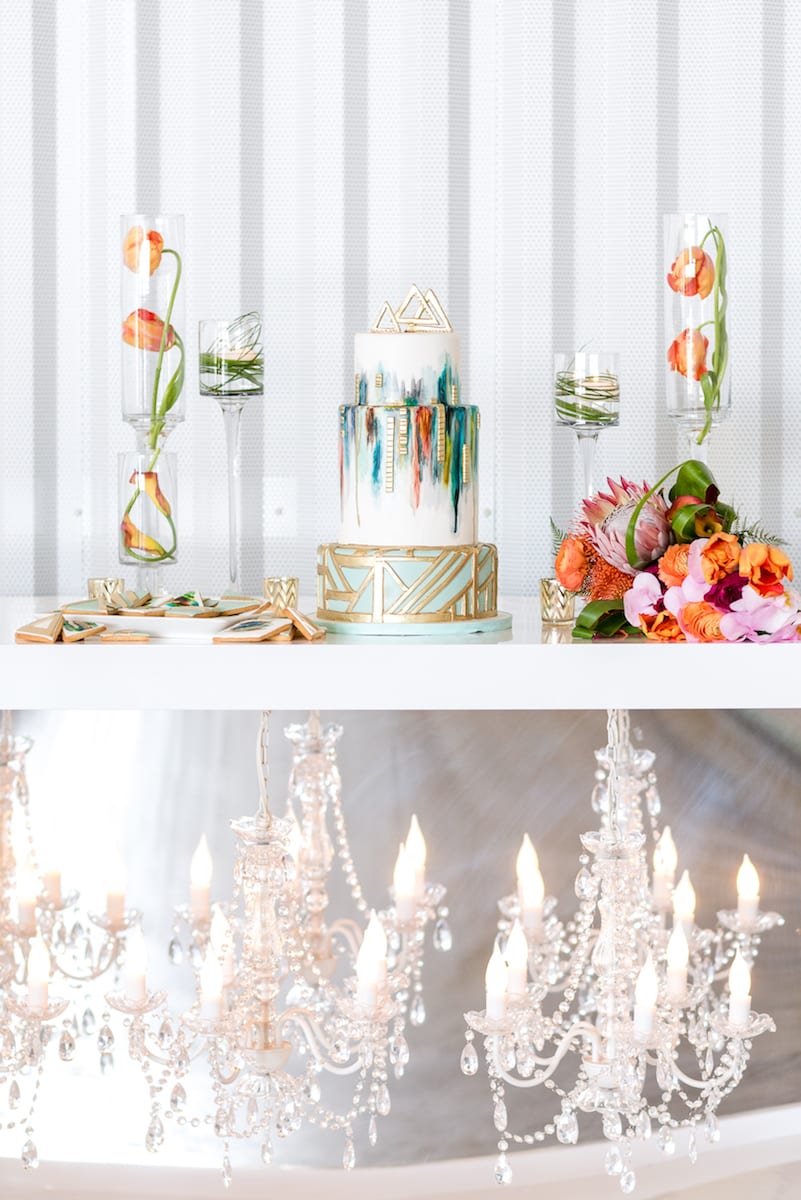 wedding cake on top of table with chandeliers hanging underneath