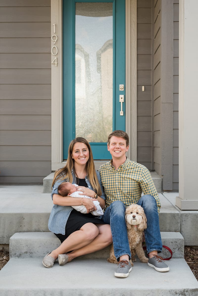 Parents holding newborn with dog in photo