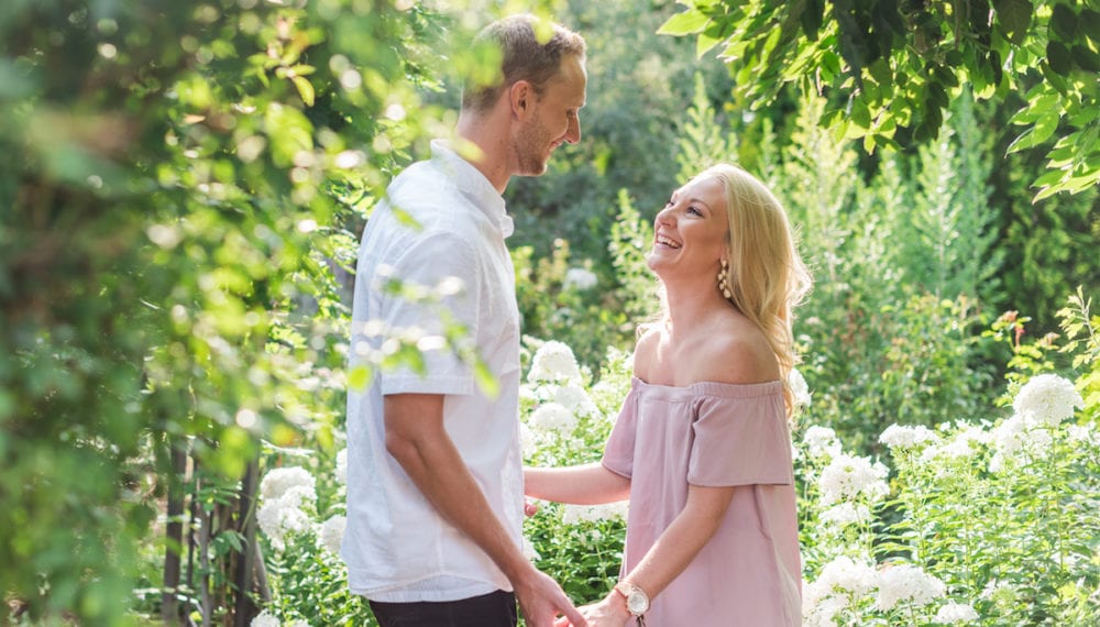 Man holds woman's hands amidst foliage at Botanic Gardens