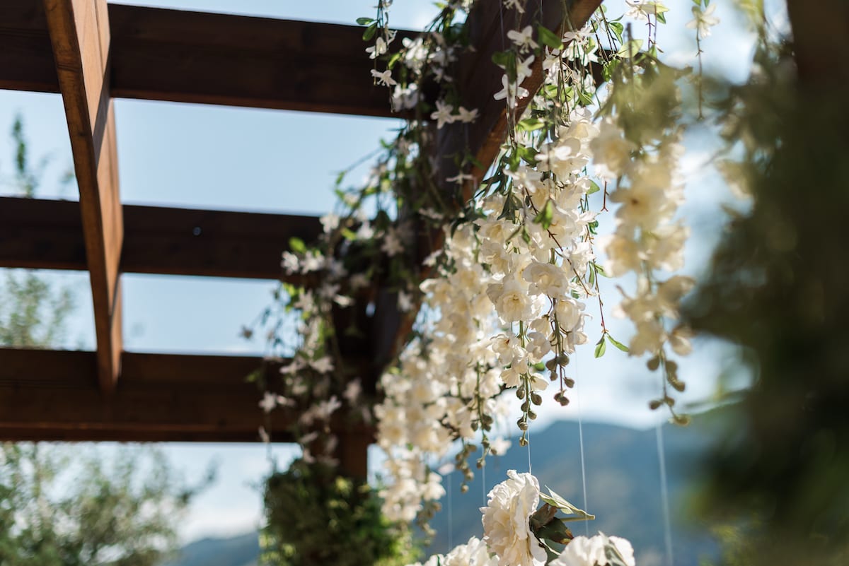 Bride in flowing white gown stands gracefully with mountain peaks visible in the distance at Willow Ridge Manor