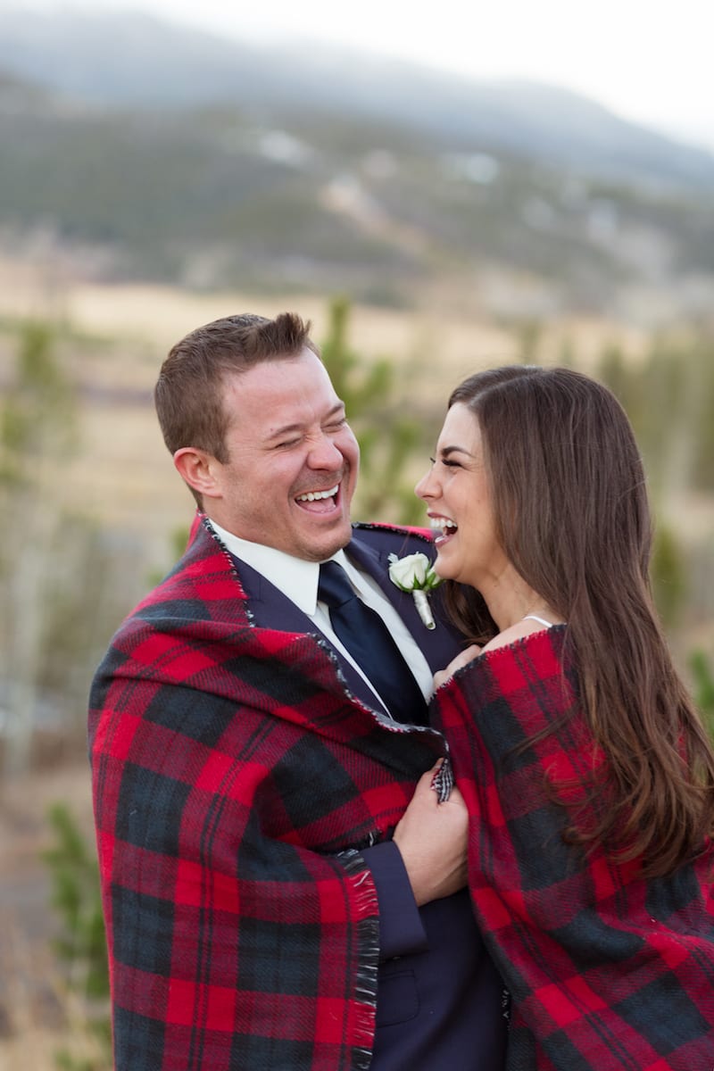 keep warm during a winter wedding | Wedding Photography | From the Hip Photo | bride and groom huddle together in a red flannel blanket while laughing