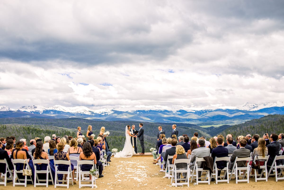 Bride and groom exchanging vows with mountain valley backdrop at Granby Ranch
