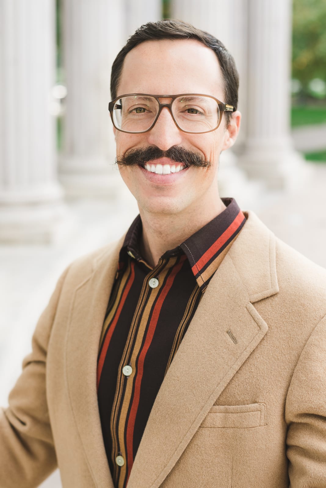 Professional headshot showing natural posing and approachable expression against studio backdrop