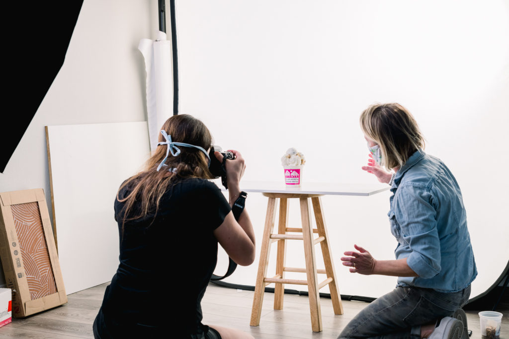 Product Photography | Two women taking photos of opened ice cream pint on white background | High Point Creamery, Denver, Colorado