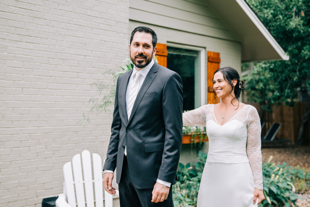 Wedding photo | Smiling bride teases groom with his back to her