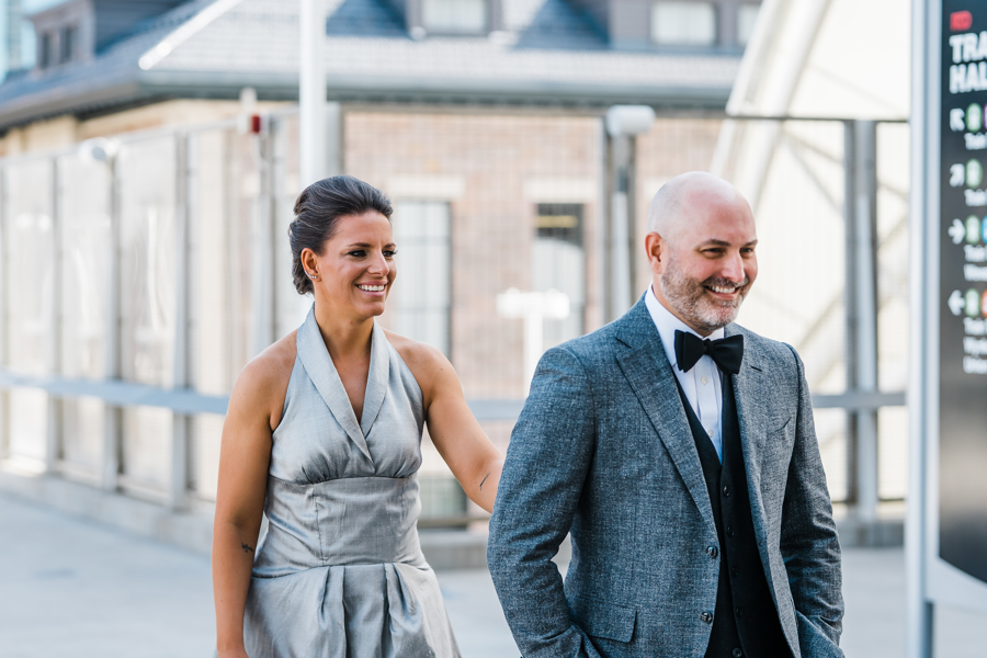 Wedding photography | Smiling bride in gray dress follows gray suited groom | Planning First Look Photos for Your Wedding