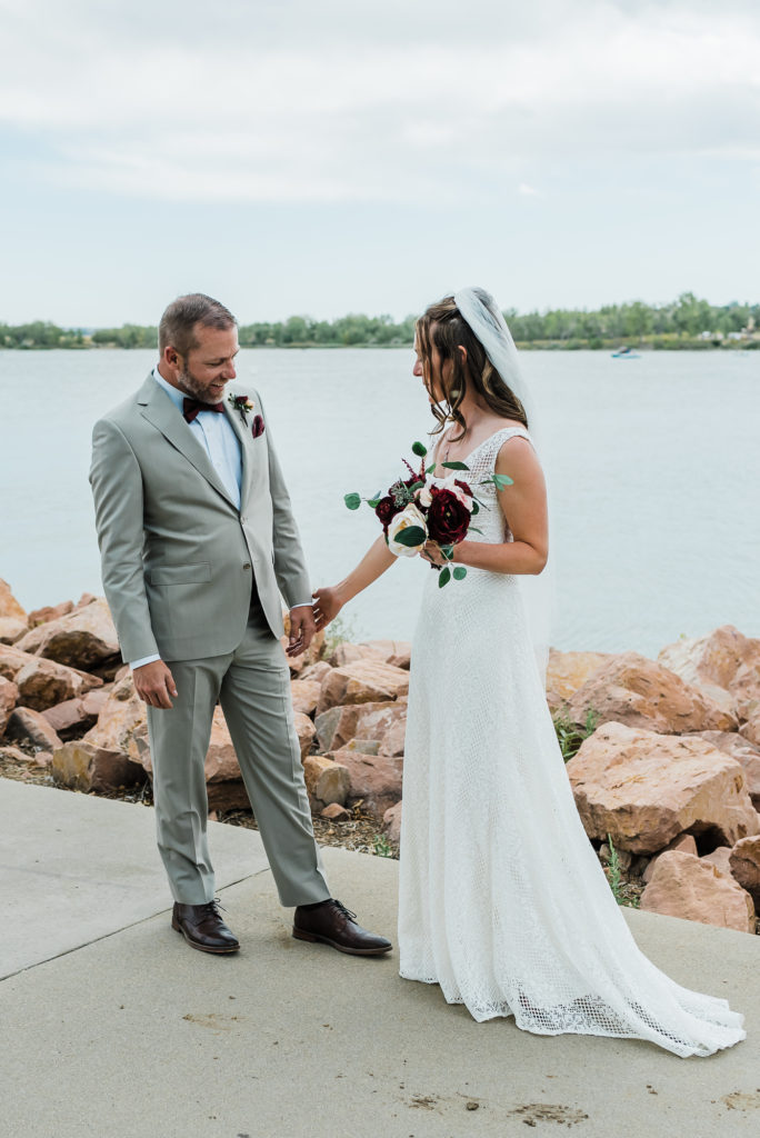 Wedding photography | Bride takes groom's hand by lake | Planning First Look Photos for Your Wedding