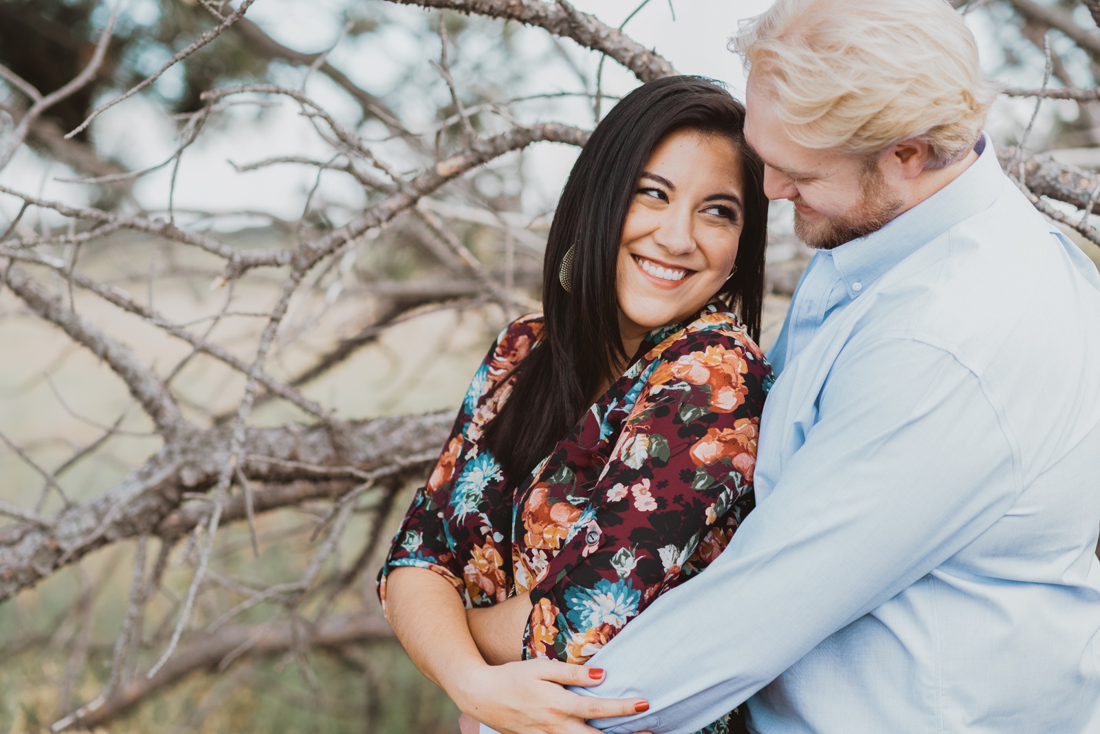 Engaged couple posing affectionately with Flatirons mountains and golden grass