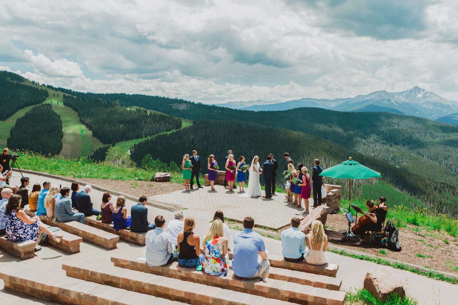 Bride and groom standing on mountain wedding deck overlooking Gore Range with dramatic peak views