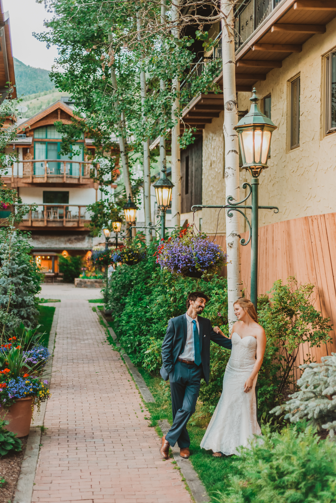 Groom in suit holding bride in white wedding dress with mountain valley scenery behind them