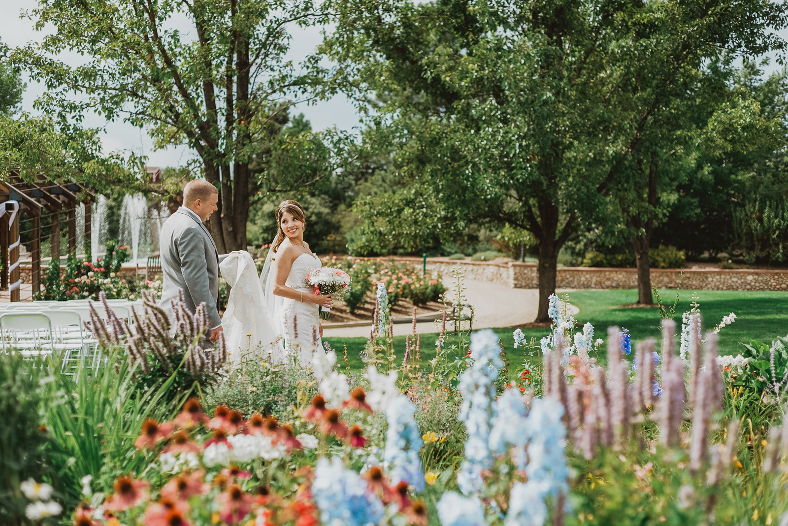 Engaged couple walking hand-in-hand through Hudson Gardens with flowering plants