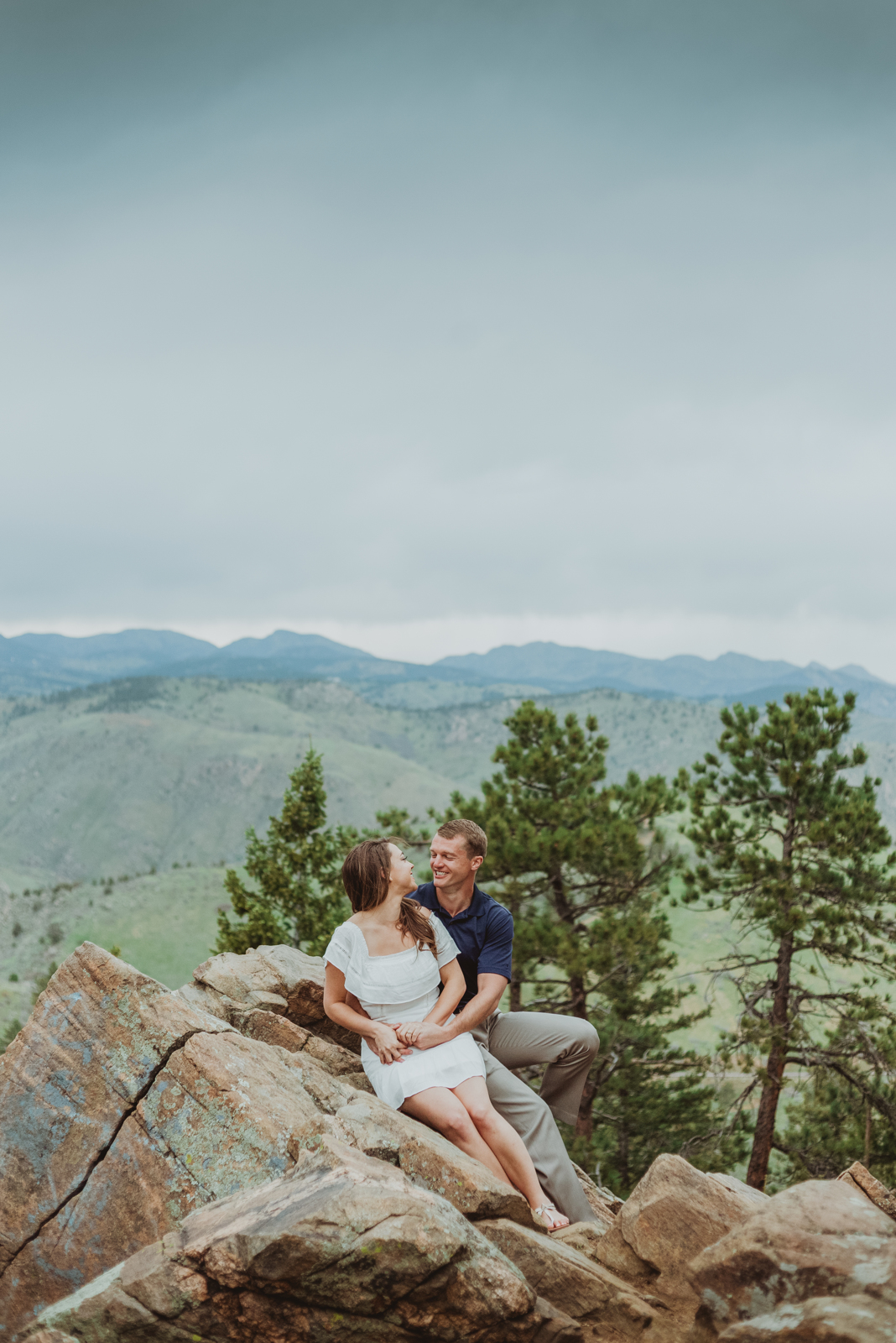 Bride and groom couple in formal attire standing together at scenic mountain overlook during sunset