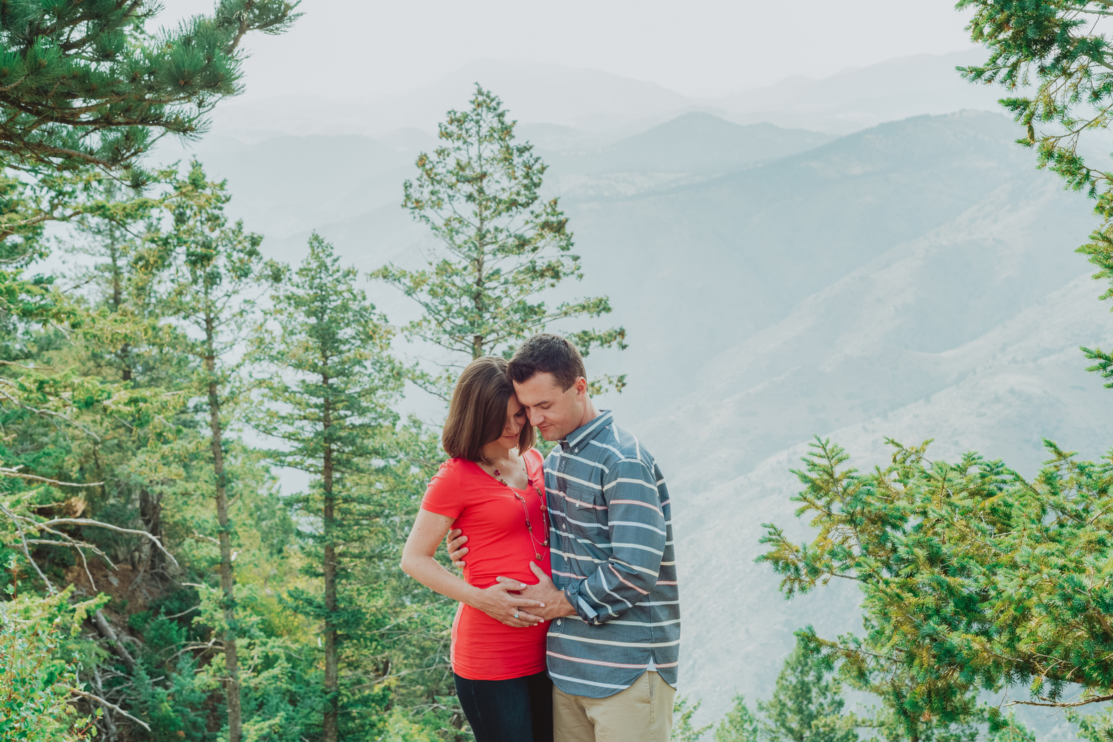 Pregnant woman in flowing dress posing among trees at Lookout Mountain during maternity photo session