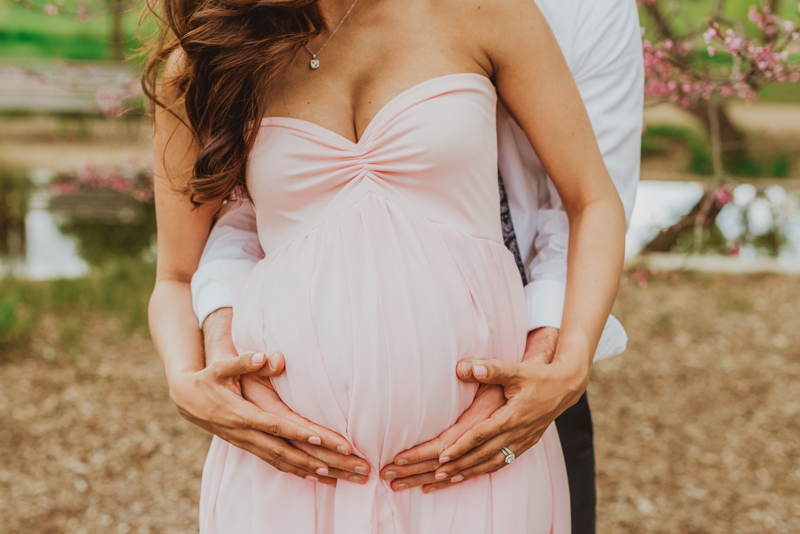 Maternity session showing expecting mother in garden with partner's embrace