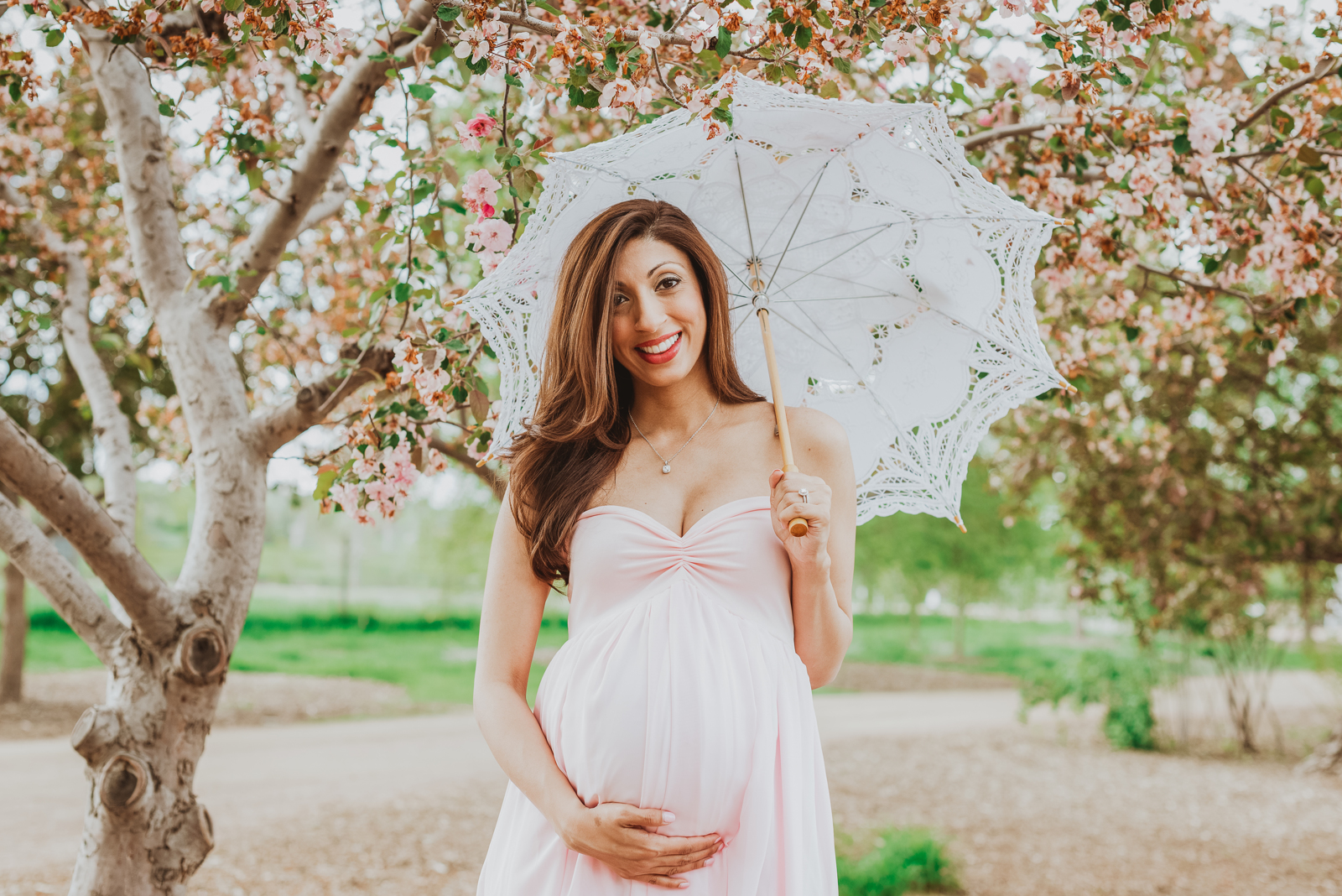 Pregnant woman in maternity gown posing gracefully in Hudson Gardens among blooming flowers