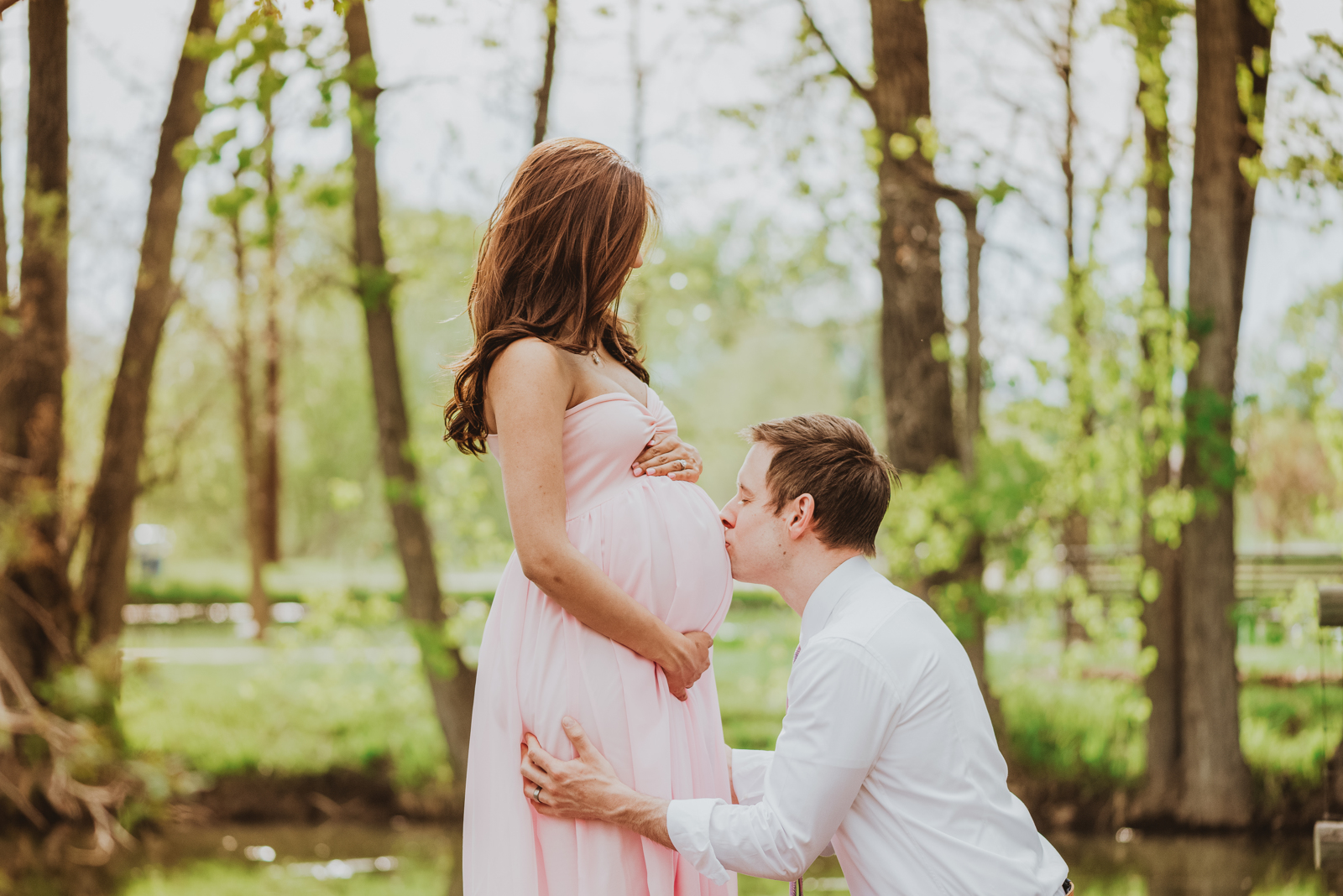 Maternity portrait showing expectant mother in soft light surrounded by blooming flowers