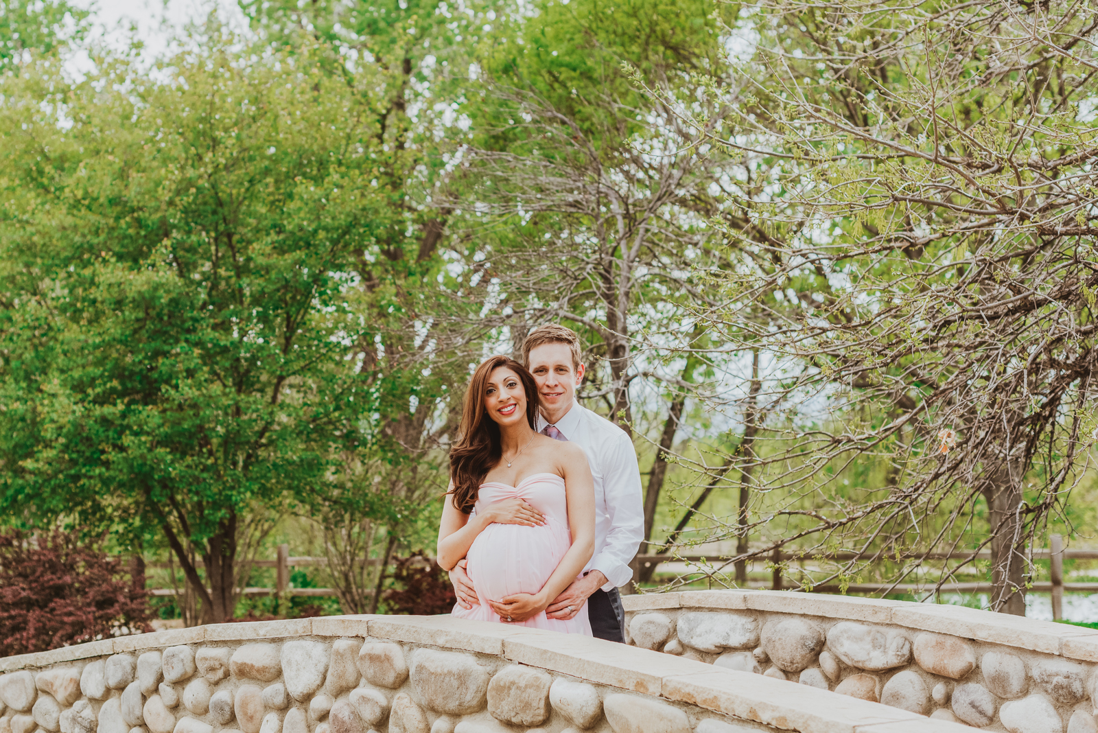 Expectant mother in maternity portrait posing among lush garden flowers and greenery