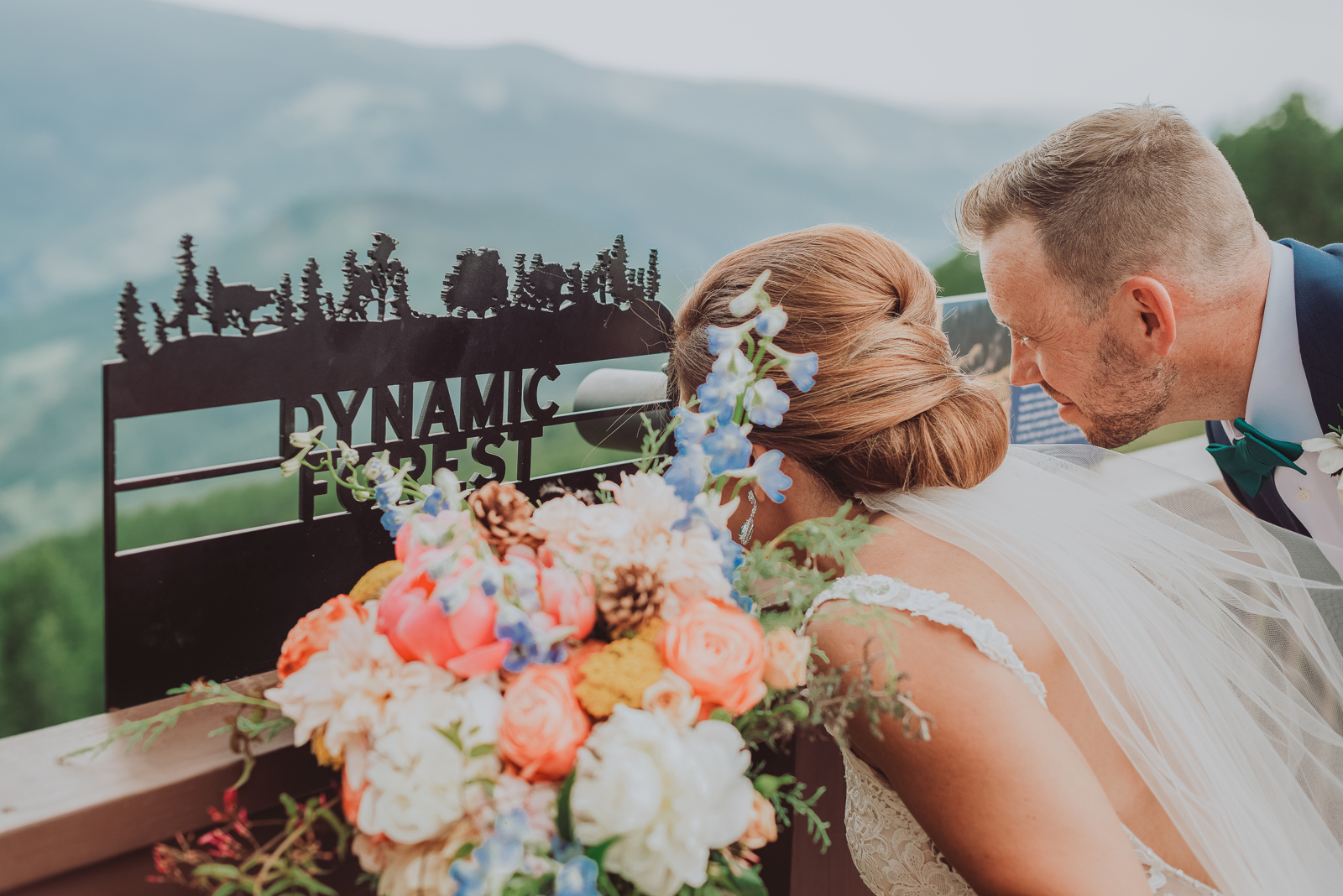 Couple in formal attire embracing with aspen forest and alpine peaks framing the shot