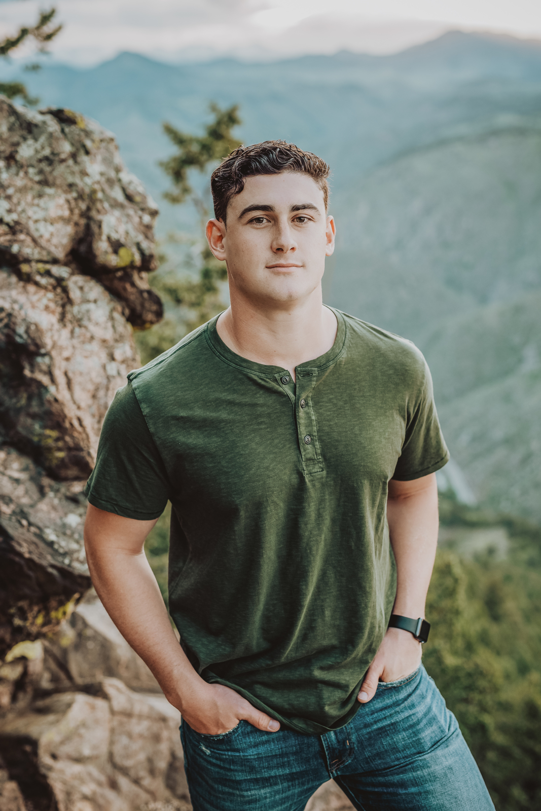 High school senior girl posing on rocky overlook in formal attire for senior portrait session