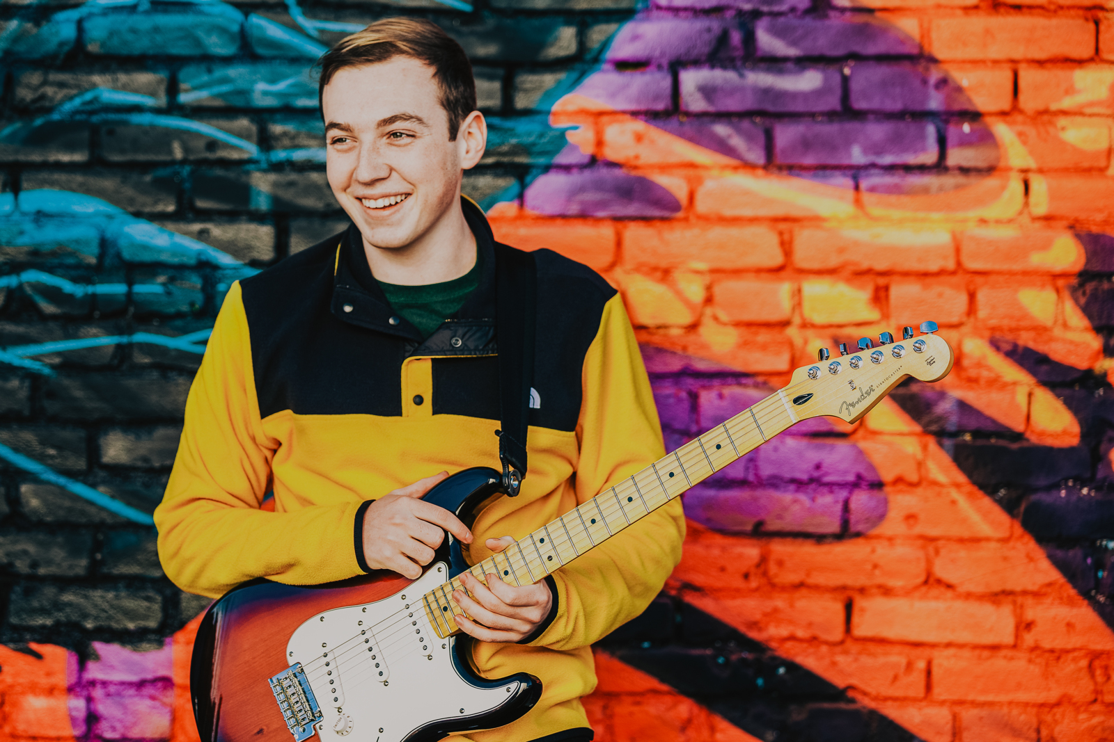 Urban senior portrait with graffiti wall and warm light in RiNo neighborhood Denver