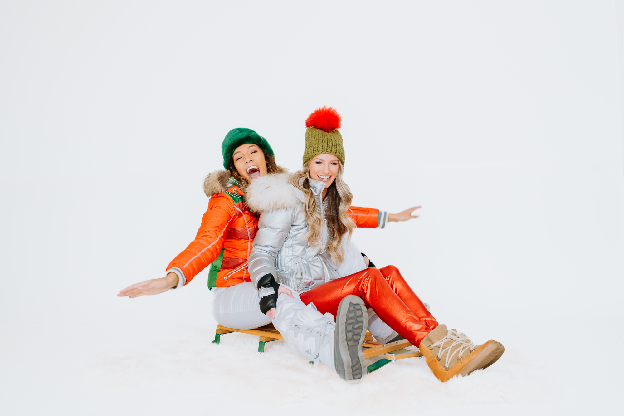 Super G Brand Photography | Two models wear winter gear sit on sleigh | Denver, Colorado