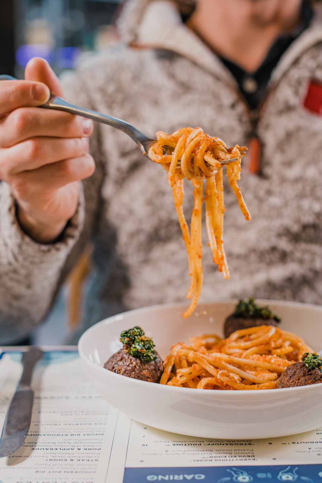 Colorado Hotel & Food Photography | The Original, The Rally Hotel | Man lifts fork wrapped in saucy coated spaghetti 