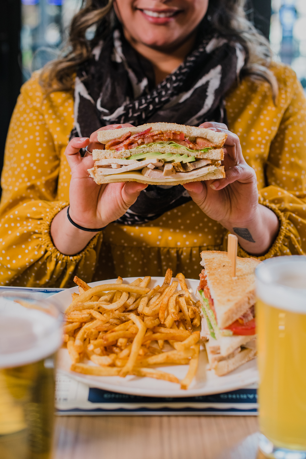 Colorado Hotel & Food Photography | The Original, The Rally Hotel | Woman picks up half of sandwich above plate of French fries