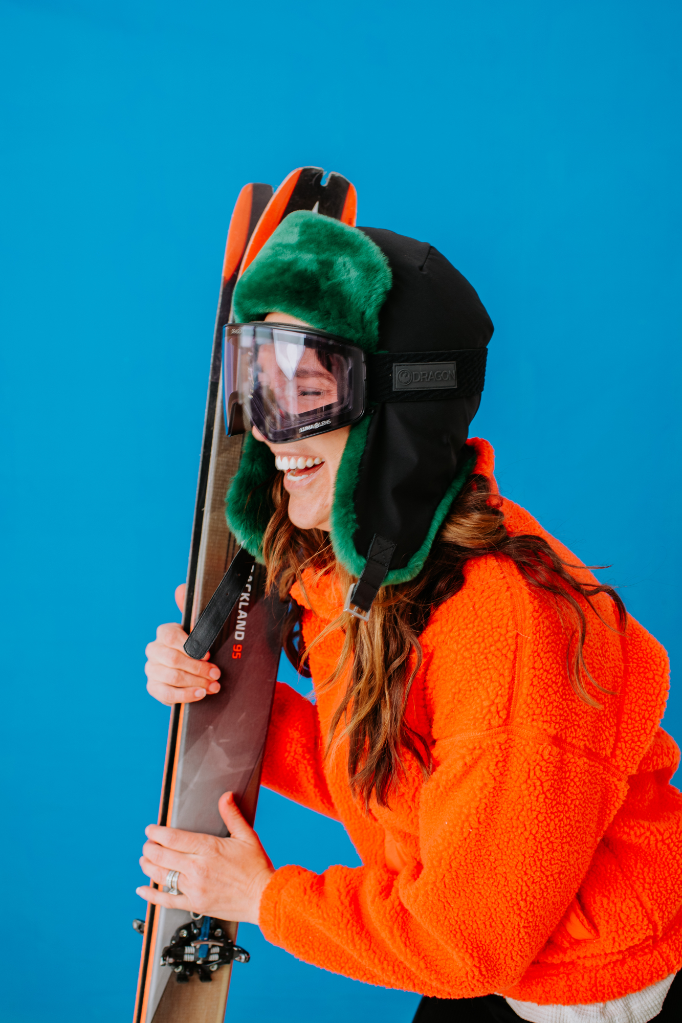 Model in Super G Brand Photography | Laughing model in ski-goggles and winter hat holding skis | Denver, Colorado