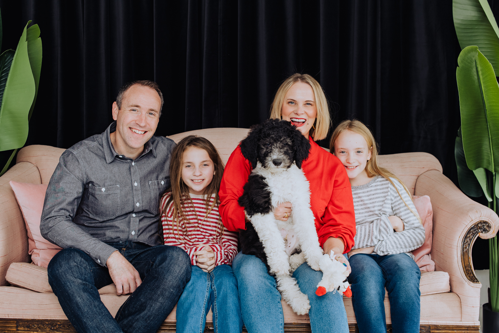 Joyful family with new puppy posing together for cheerful holiday family photo in Denver studio