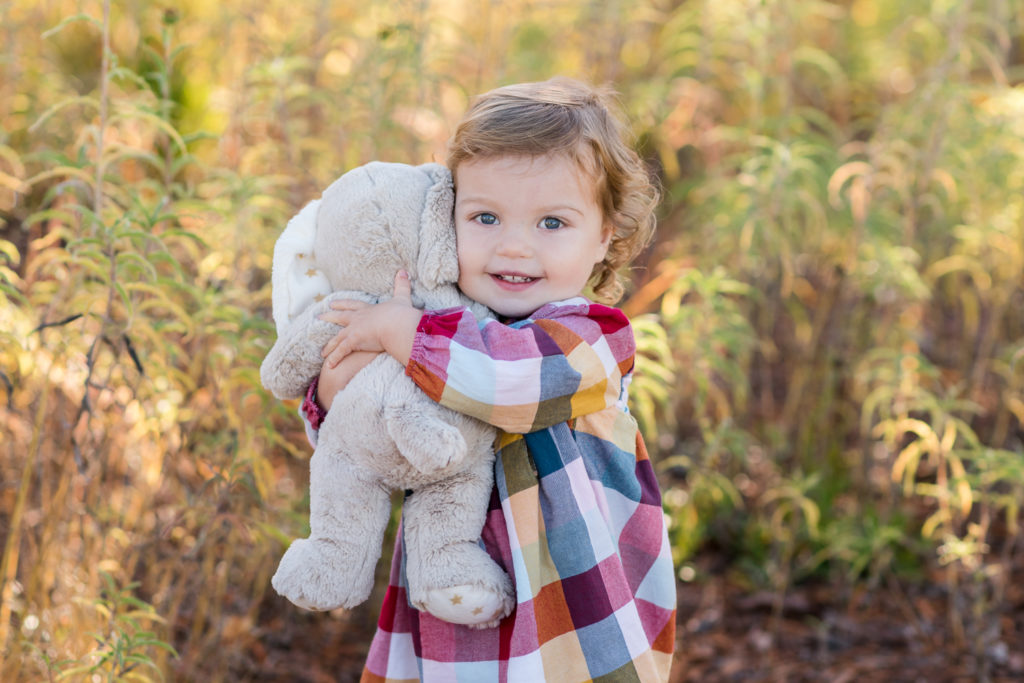 Newborn photography | Happy baby hugs her favorite stuffy with a fall autumn background