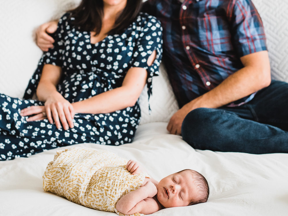 Newborn family photography | Sleeping baby with his parents behind them on the bed