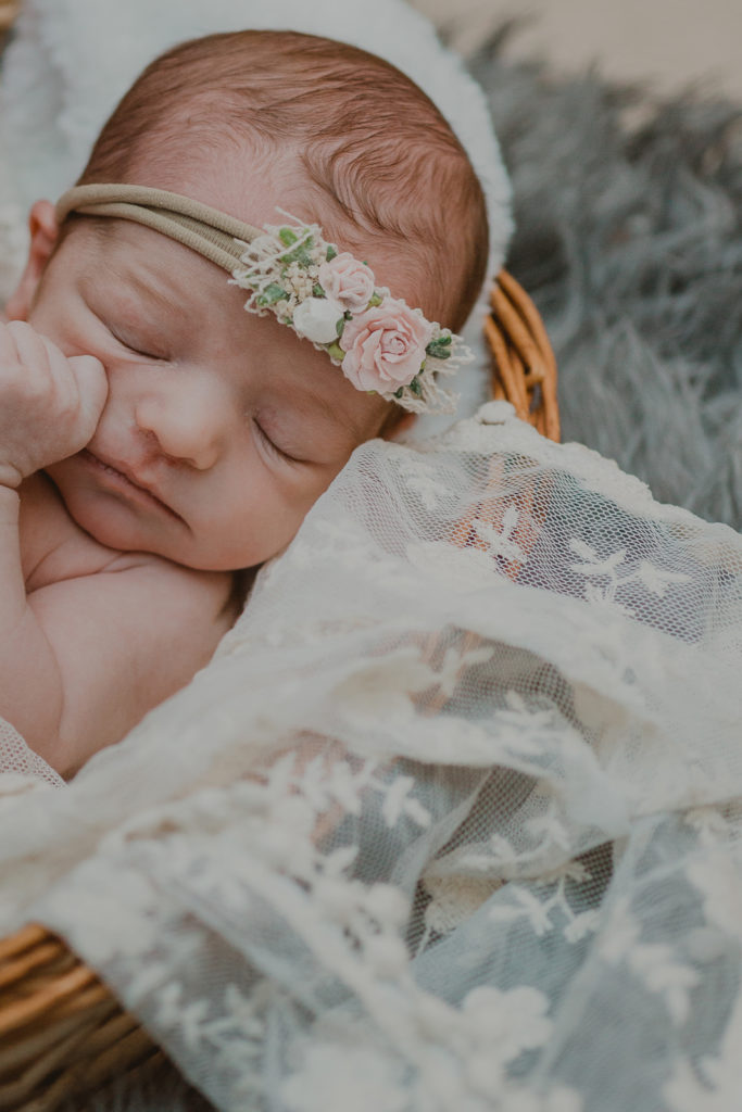 Newborn photography | Sleeping baby in a wicker basket with a floral headband