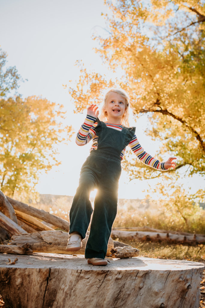 Colorado Fall Family Photo Tips | Little girl smiles with setting sun and autumnal colors
