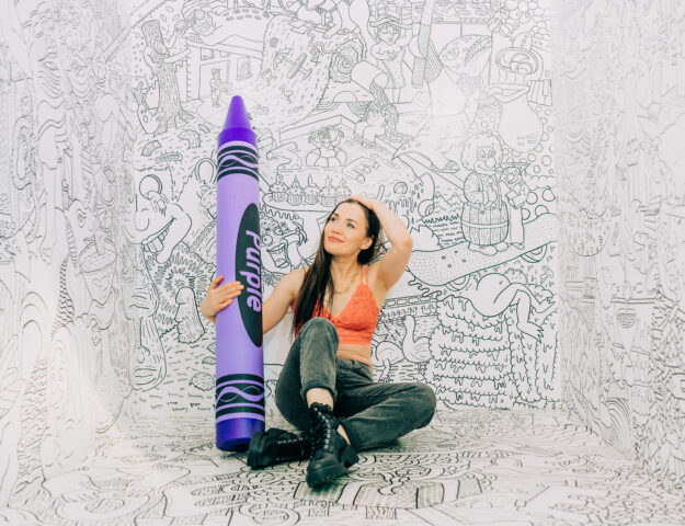 Varya Malina from "90 Day Fiancé" posing with giant purple crayon at Denver's Selfie Museum