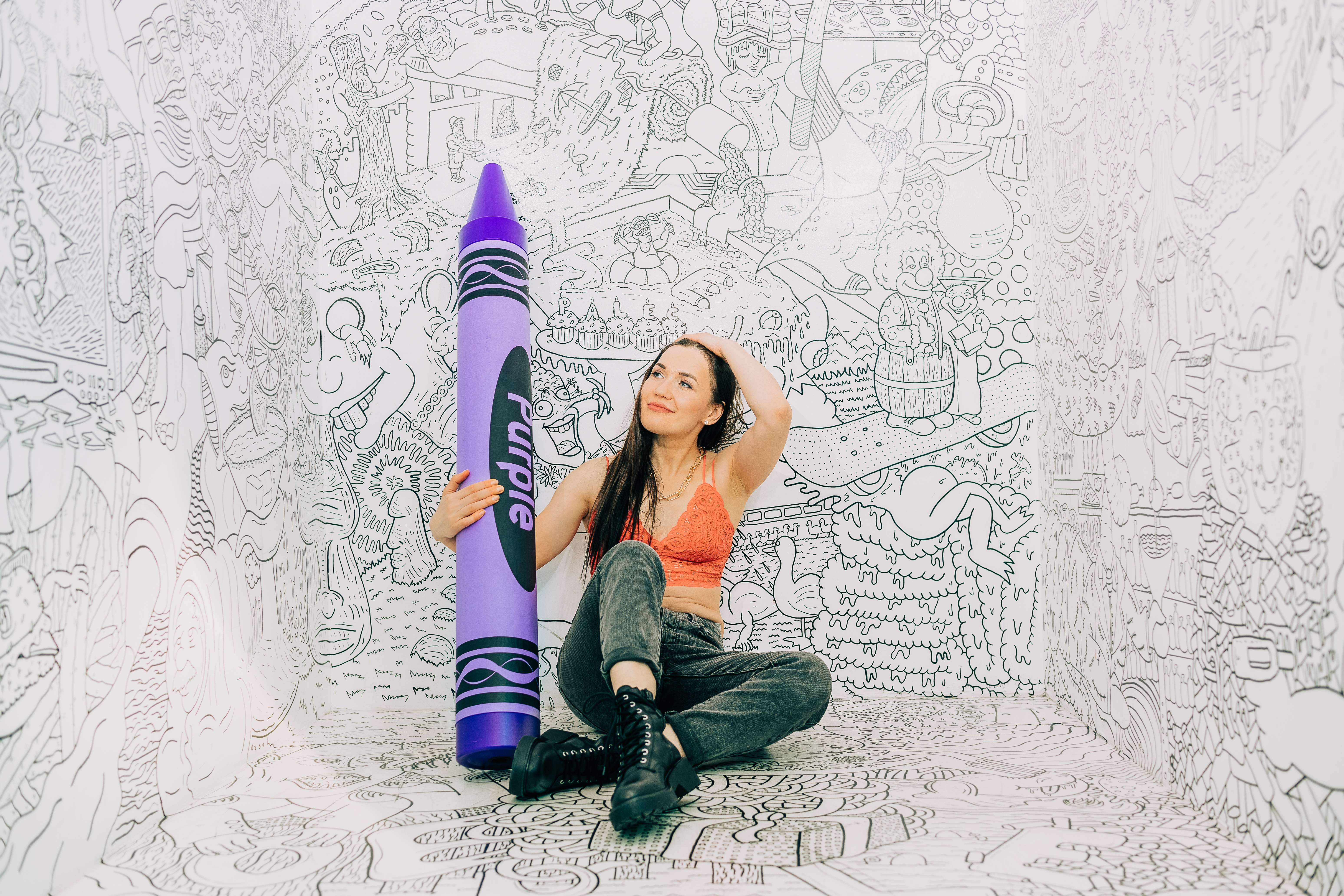 Playful creative portrait with an oversized purple crayon prop at the Denver Selfie Museum