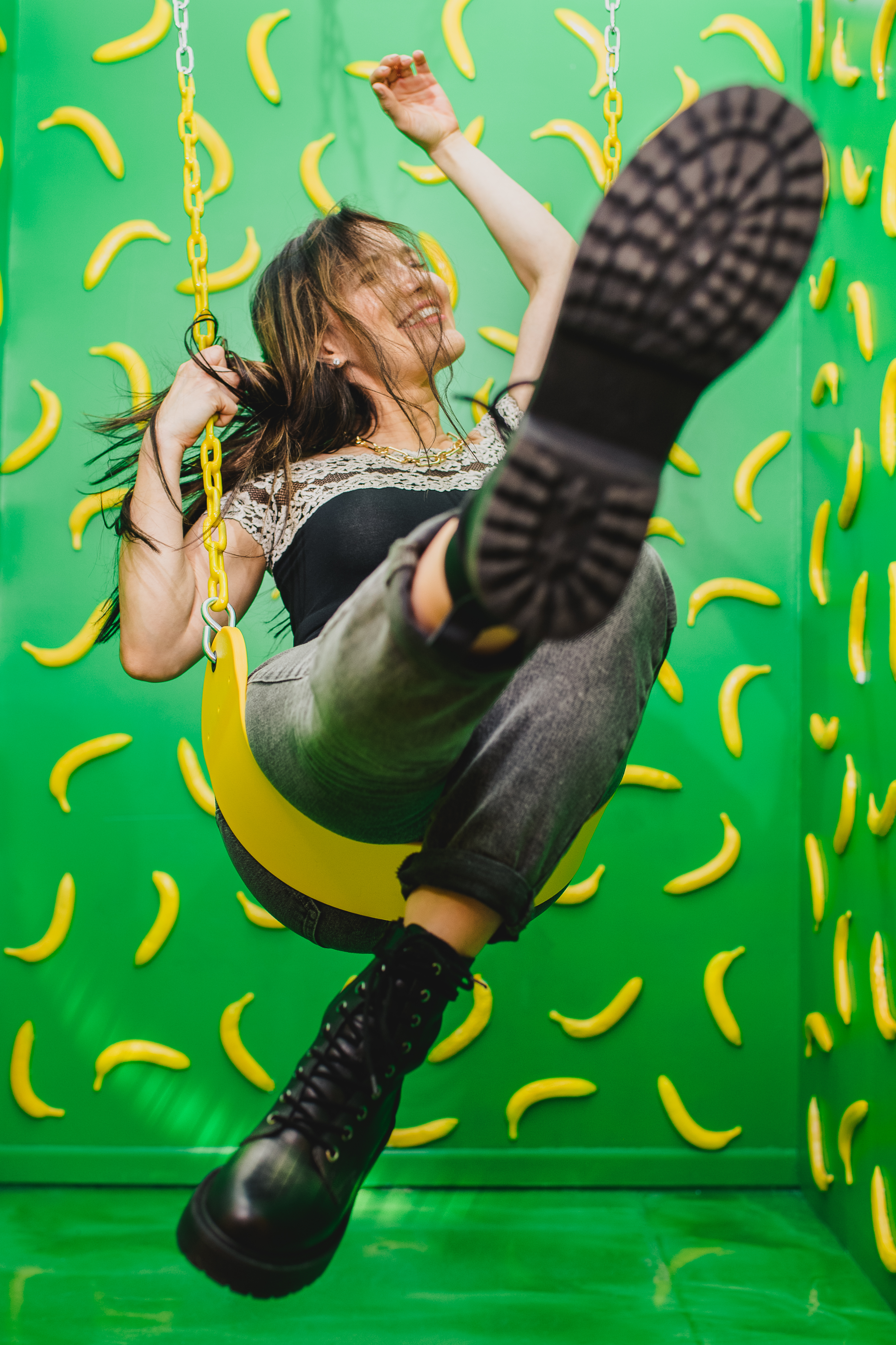 Joyful portrait on a swing surrounded by tropical banana leaf decor at the Denver Selfie Museum