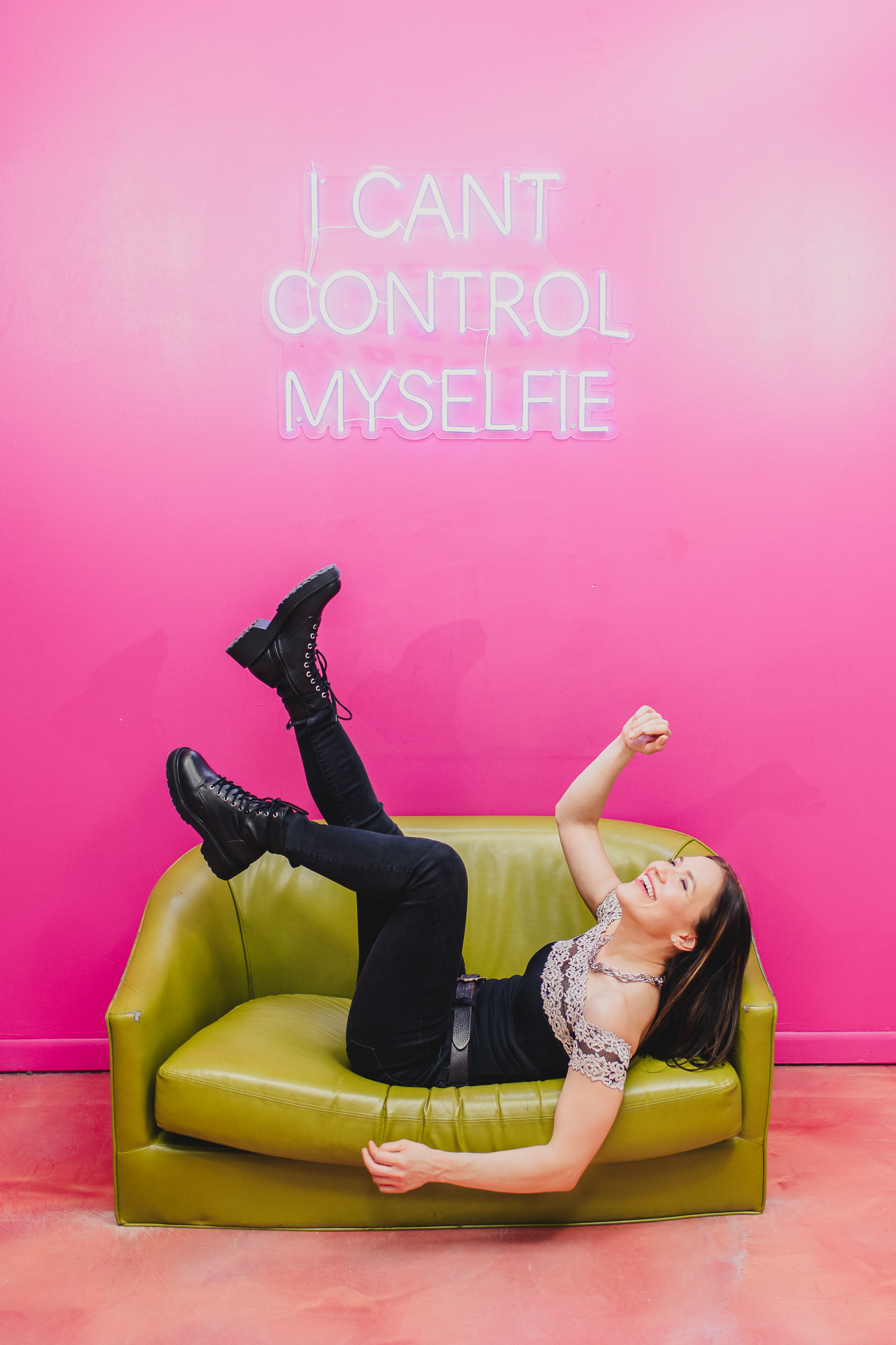 Woman laughing naturally on a colorful couch during a creative portrait session at the Denver Selfie Museum