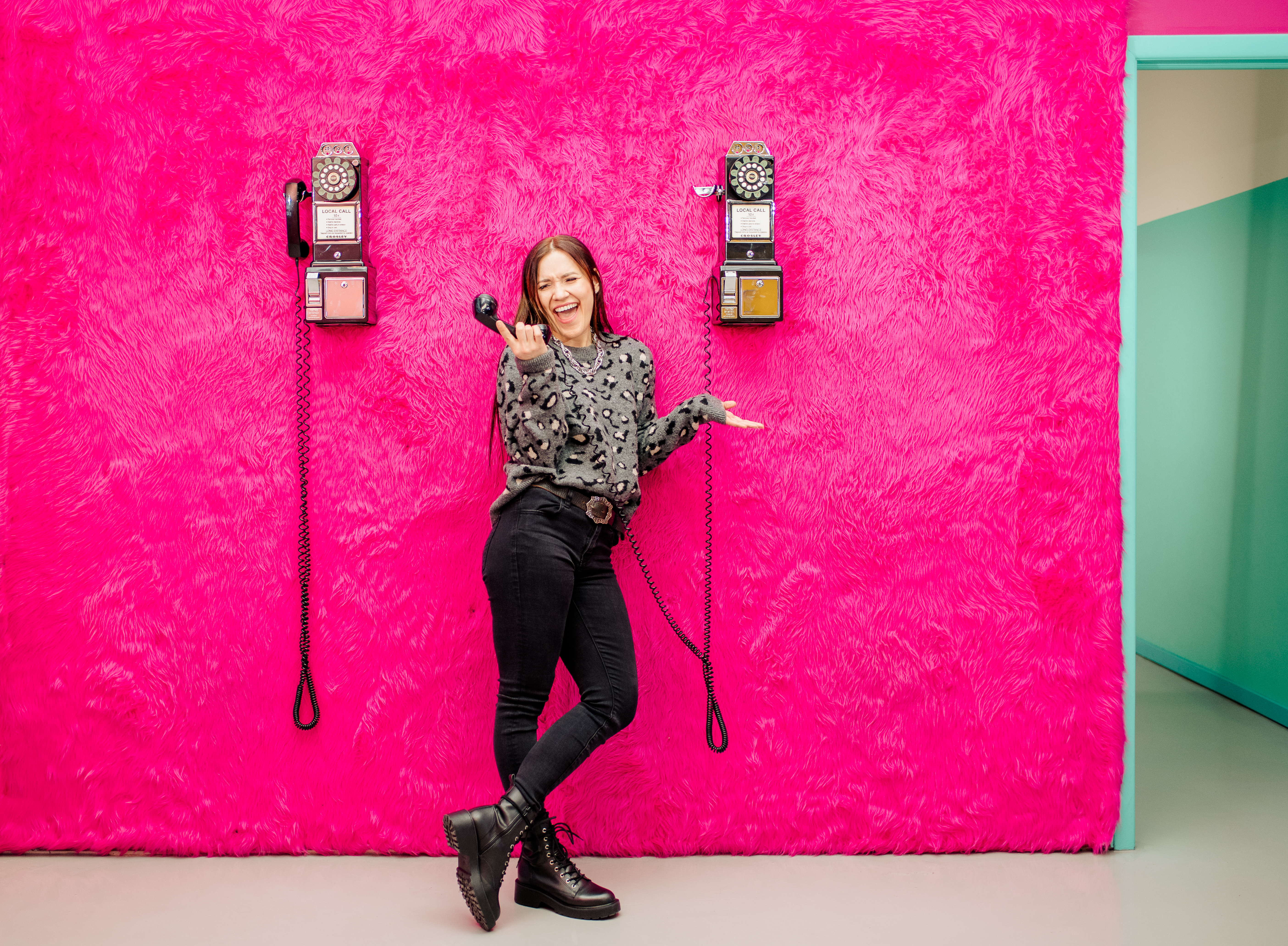 Creative lifestyle portrait talking on a vintage phone in a pink room at the Denver Selfie Museum