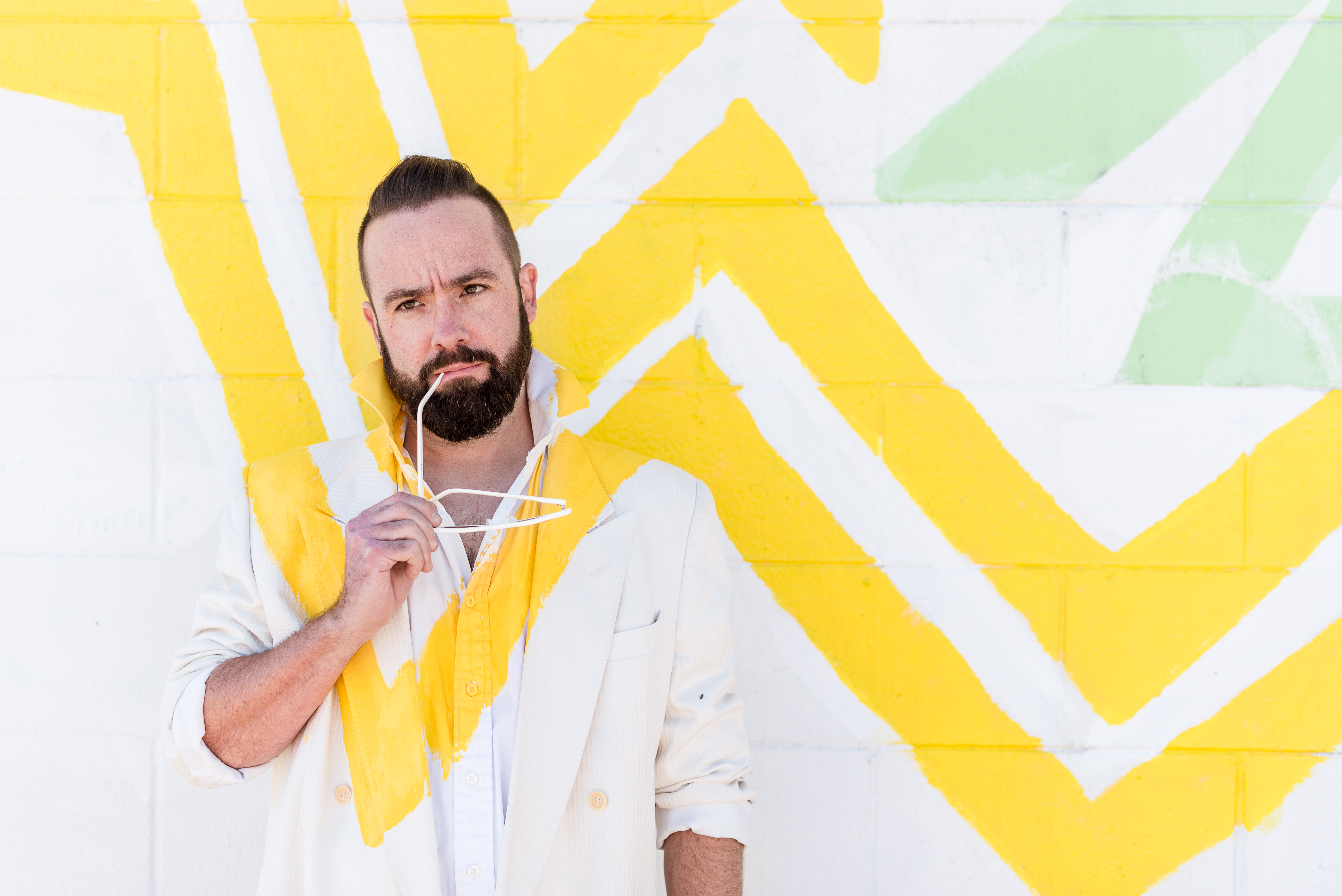 Man standing in front of an art wall that perfectly matches his outfit during a Denver portrait session