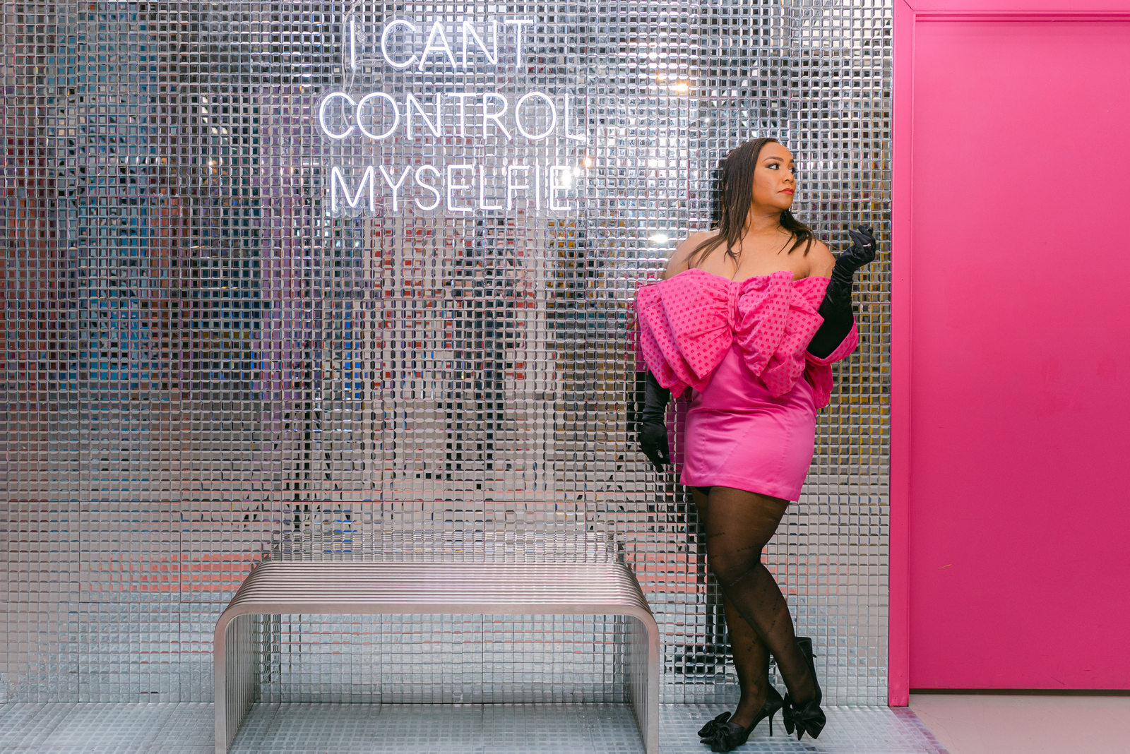 Fashion-forward portrait of a woman in a vintage pink dress at a colorful Denver Selfie Museum installation