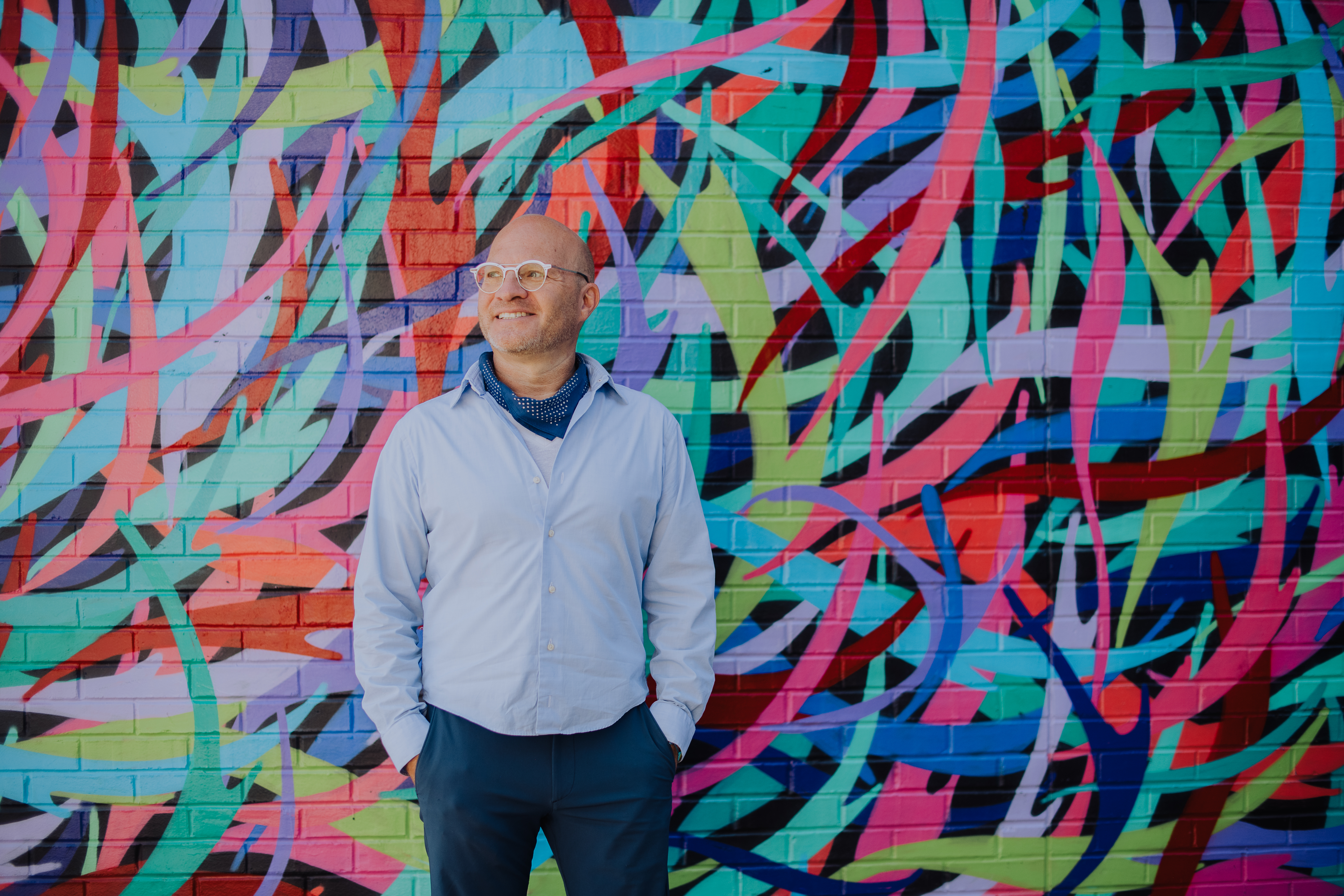 Professional creative headshot of a man posing in front of colorful street art in Denver RiNo Art District